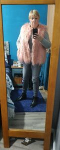 Me in front of a mirror with a pink gillet , jeans and a jumper on