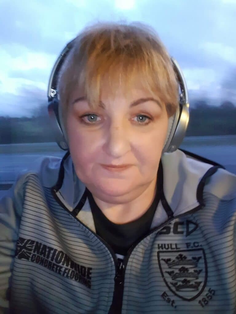 Photo of Rachael with a grey jacket on and headphones