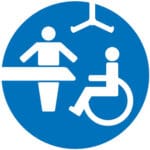 Changing places logo blue cirlce with the shape of a wheelchair, a person standing next to a changing couch.